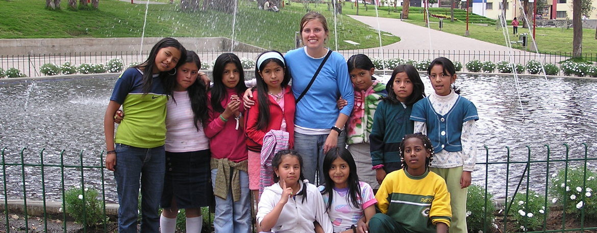 Volunteer with students in front of fountain in Ecuador