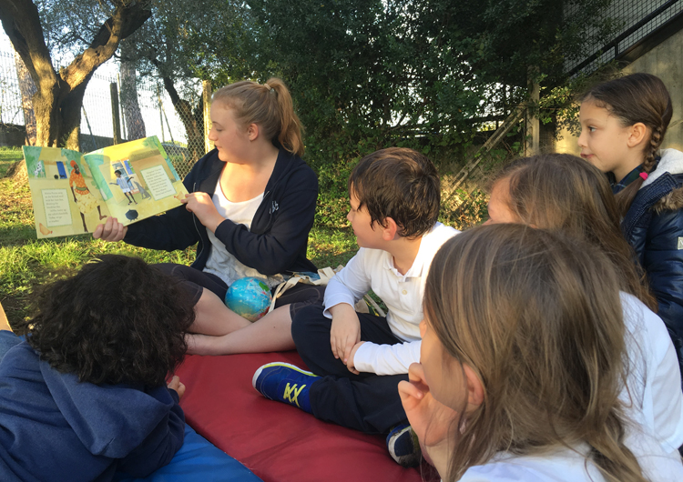Some students and a teacher reading together outdoors.