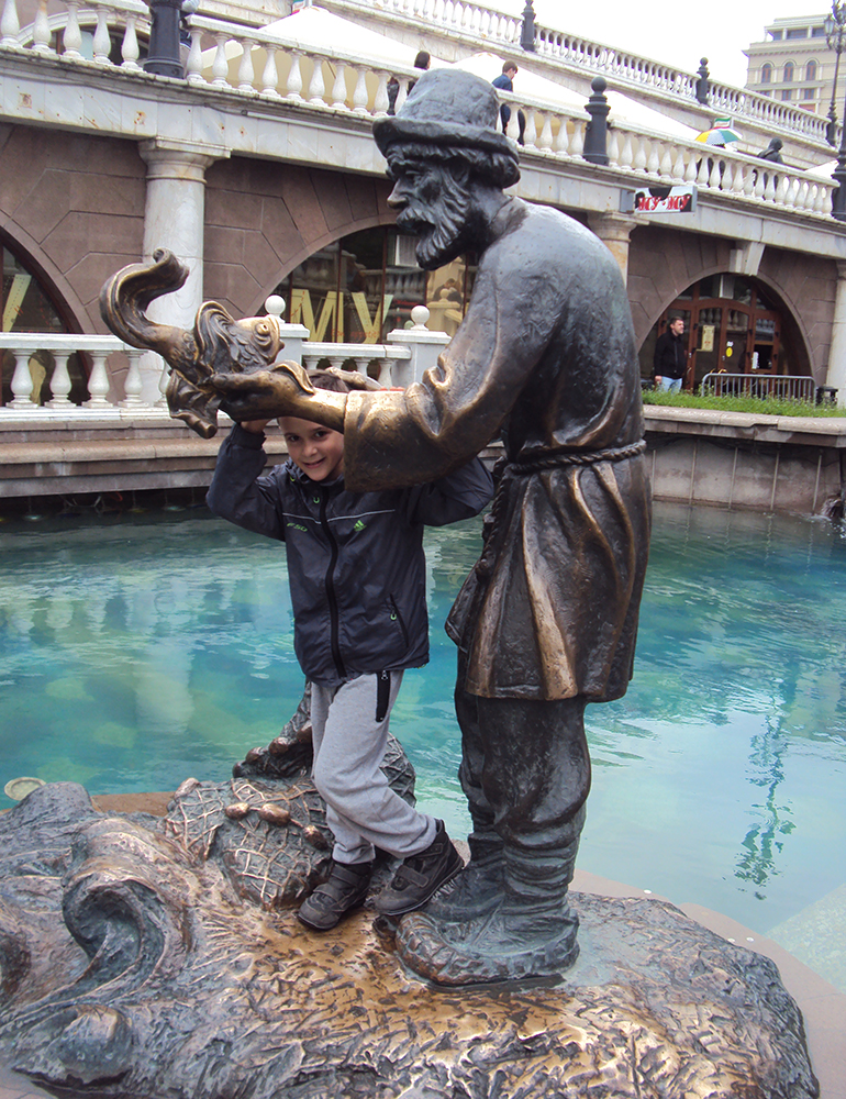 A child hanging off a statue of an old man.