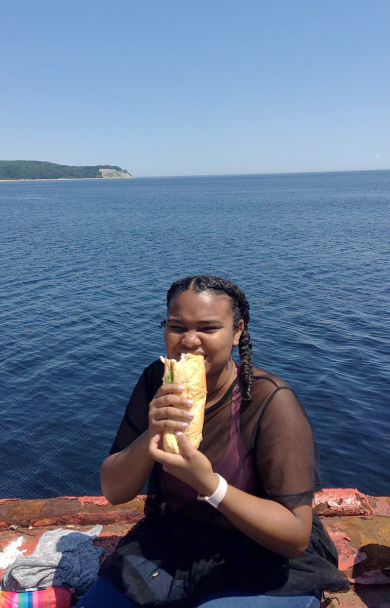 Greenheart Traveler, Kyra Hymons, eating lunch near water in Quebec, Canada.