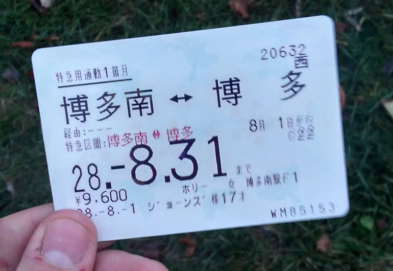 Fingers gripping a train ticket in Japan.