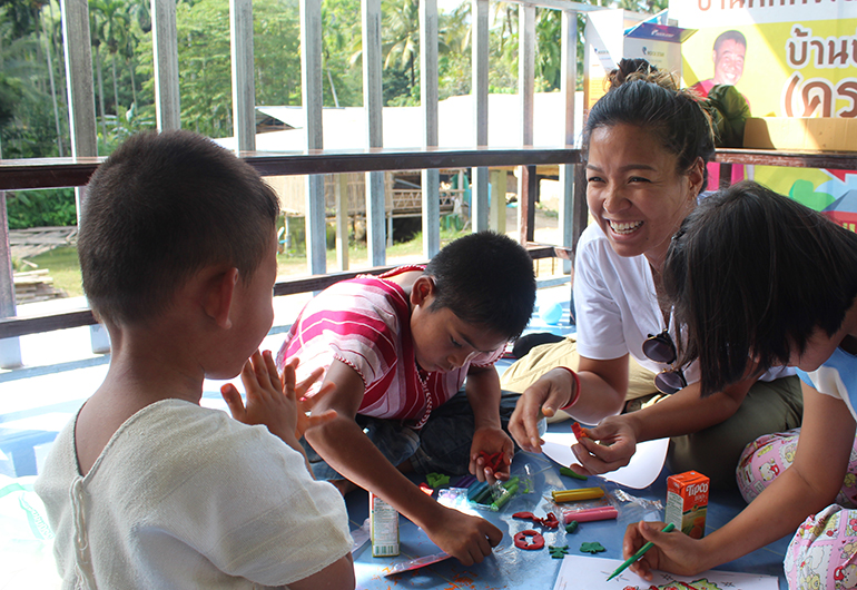 A Greenheart Travel teacher laughing with some students in Thailand.