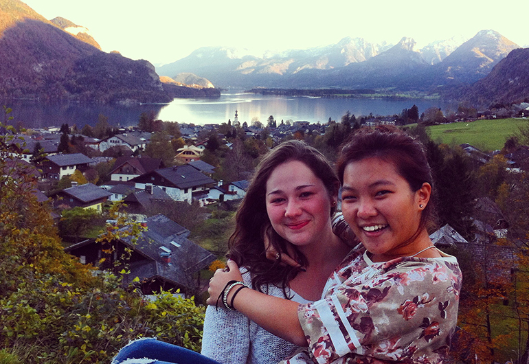 Two study abroad students hugging each other in Salzburg, Austria with mountains in the background.
