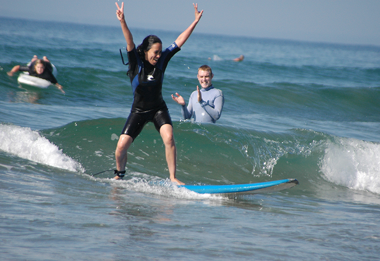 Student triumphantly riding a wave in Australia.