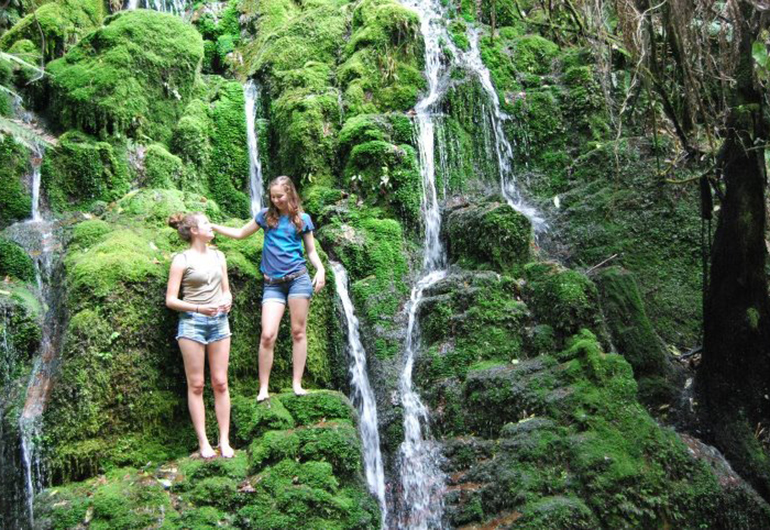 Two students climbing the waterfalls in New Zealand.