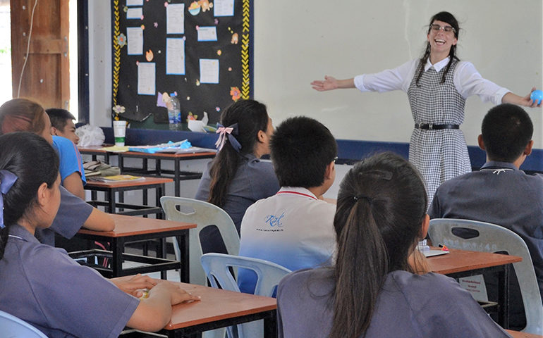 A teacher demonstrating something in front of her class in Thailand.
